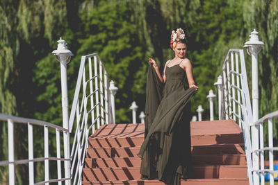 Woman standing by railing against plants