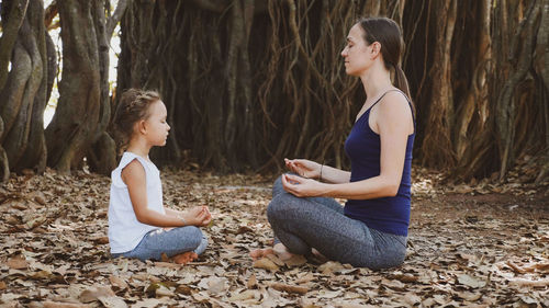 Side view of two women sitting on land