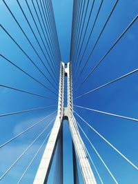 Low angle view of suspension bridge against blue sky