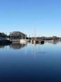 Sailboats moored in lake against clear blue sky