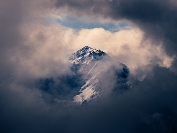 Clouds covering snowcapped mountain