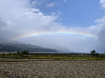 Scenic view of field against rainbow in sky