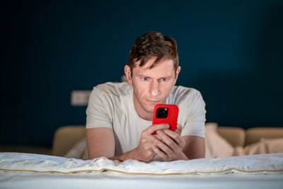 Man uses smartphone lying on bed. online internet purchases solving business problems conducts chat