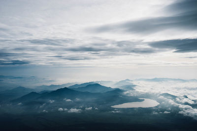 Aerial view of mountains against cloudy sky during sunny day