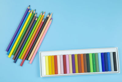 Close-up of multi colored pencils on table against blue background