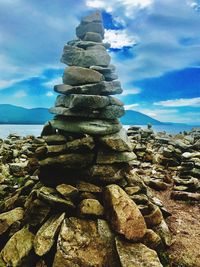 Stack of pebbles by sea against sky