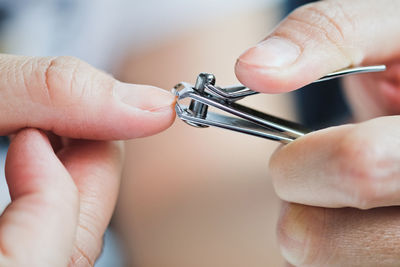 Cropped hands of woman cutting nails with clipper