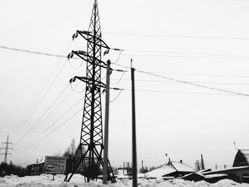 Low angle view of electricity pylon against sky during winter