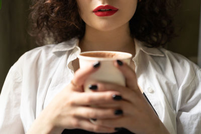 Midsection of woman drinking coffee