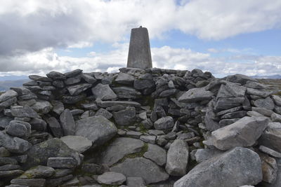 Stone wall by rocks against sky