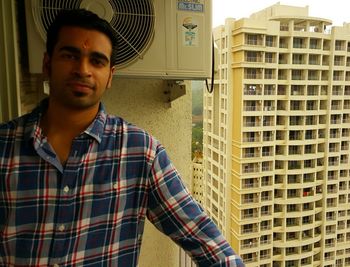 Portrait of a young man standing in front of building