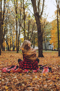 Woman sitting on sidewalk during autumn