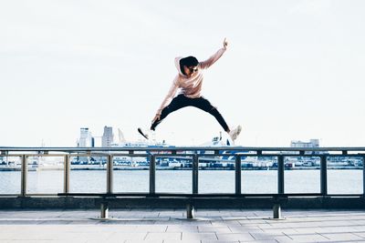 Full length of young man jumping against clear sky