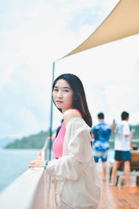 Portrait of young woman standing against sea