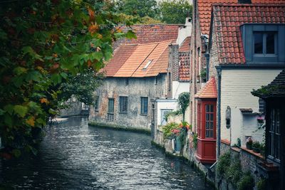 Houses by river amidst buildings in city