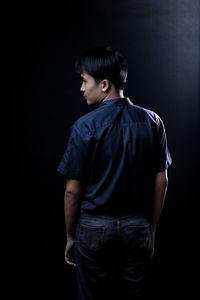 Young man standing against black background