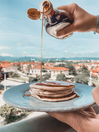 Midsection of person holding pancake against sky