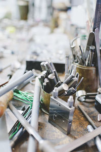 High angle view of various tools in container on workbench at jewelry workshop