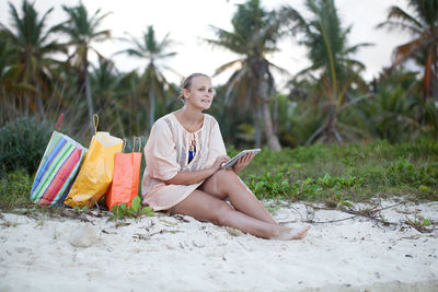 Young woman relaxing on sand at beach during sunset