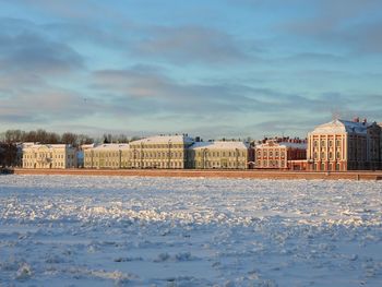 Buildings on snow covered field against sky