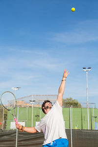 Young man playing tennis against sky