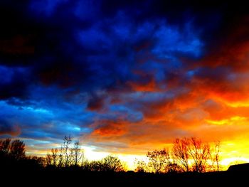 Low angle view of silhouette trees against cloudy sky