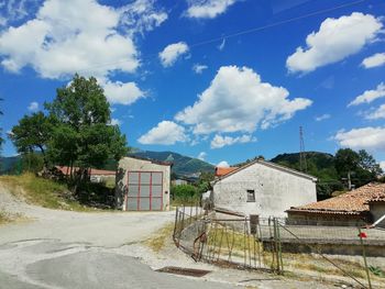 Houses and trees by road against sky