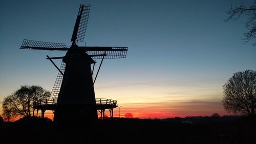 Silhouette of windmill against dramatic sky