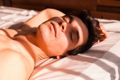 Sunlight falling on young man sleeping on bed