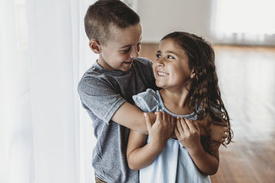 Brother and sister laughing at each other in natural-light studio