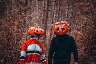 Low angle view of orange standing by pumpkins during autumn