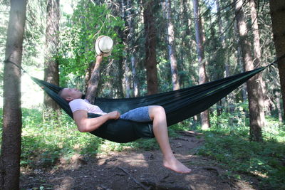 Side view of senior man on tree trunk in forest