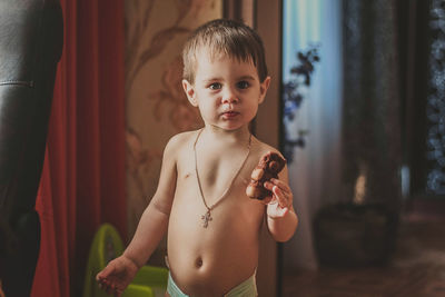 Portrait of boy holding food while standing at home