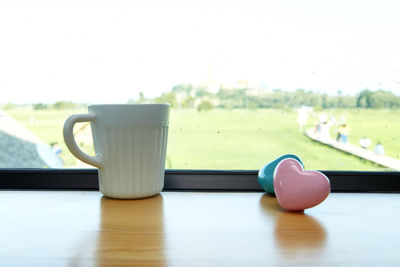 Close-up of coffee cup with heart shapes on window sill