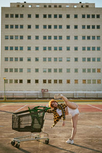 Mixed heritage asian-spanish young female dancing with shopping cart