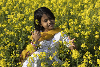 Portrait of smiling girl standing on yellow flowering plants