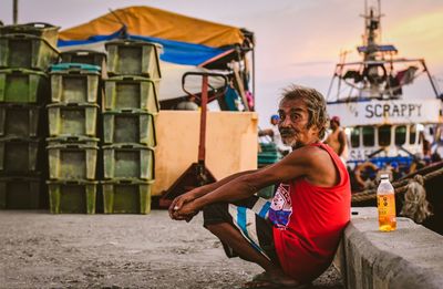 Full length portrait of young man sitting on land