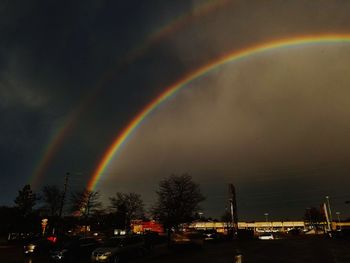 Rainbow over city against sky at dusk