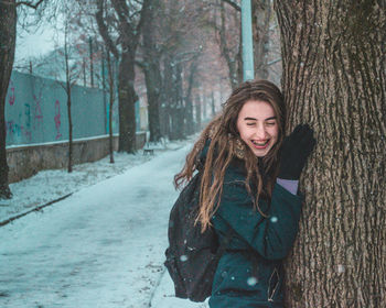 Portrait of smiling young woman in forest during winter