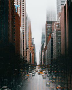 City street amidst buildings against sky during rainy season