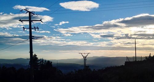 Low angle view of silhouette electricity pylon against sky during sunset