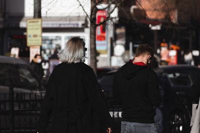 Rear view of people walking on street in city