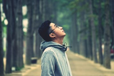 Man looking up while standing amidst trees