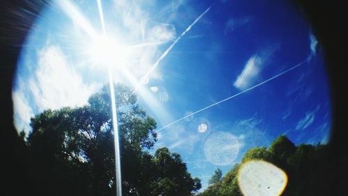 Low angle view of sun shining through clouds