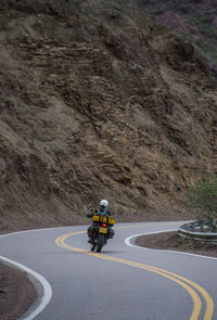 Woman on touring motorbike riding twisting road in argentina