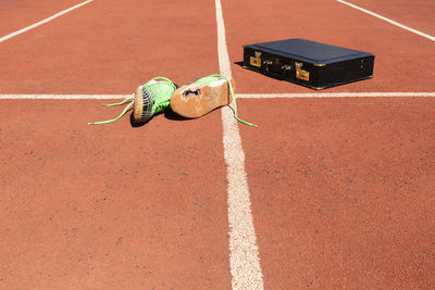 A briefcase and broken running shoes on a running track symbolizing competition and in business