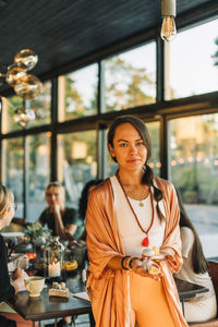 Portrait of woman holding variety of gemstones while standing at retreat center