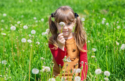 Side view of young woman picking flowers on field