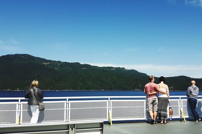 Rear view of friends standing on railing against mountain