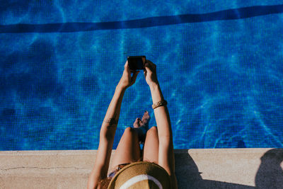 Low section of woman using smart phone at swimming pool